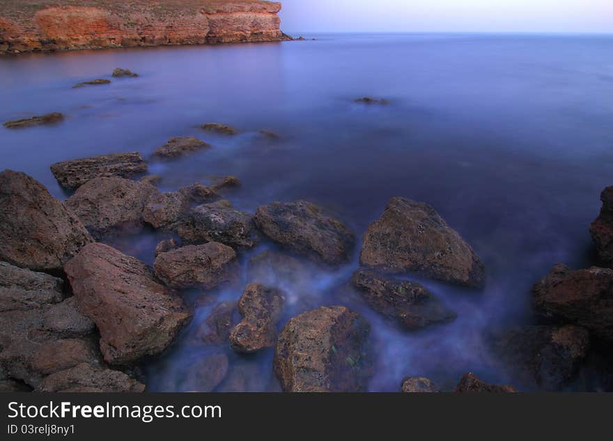 The sea stones scattered in picturesque disorder largely on seacoast with become blue water. The sea stones scattered in picturesque disorder largely on seacoast with become blue water