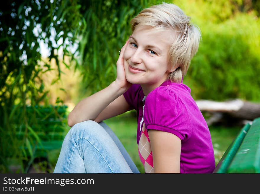 Happy attractive woman sitting on bench in park