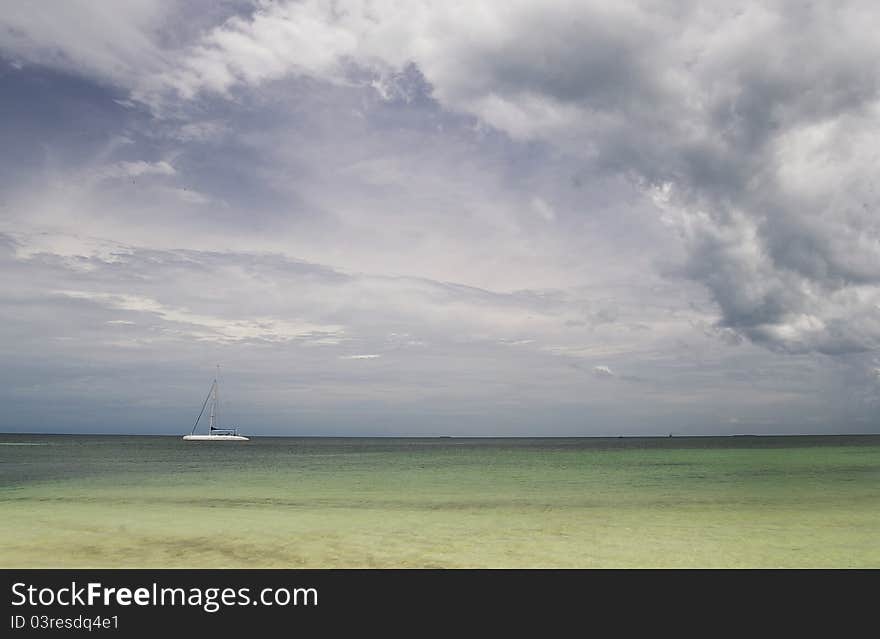 Sailing boat outside the coast of Cuba, with the sails down