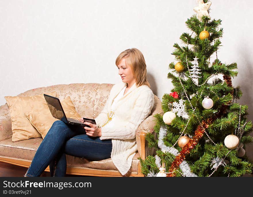 A young woman sits with a notebook near a new-year tree. A young woman sits with a notebook near a new-year tree