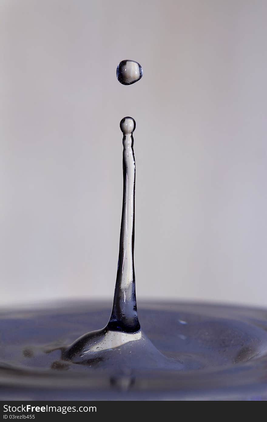 Splash from drop of water falling into pool of water, action captured with flash. Splash from drop of water falling into pool of water, action captured with flash