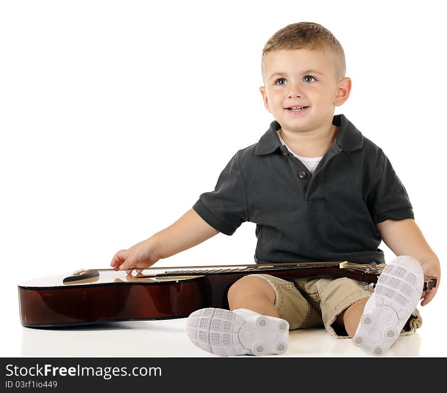 An a dorable toddler looking up as he plucks the strings of a classic guiatar. Isolated on white. An a dorable toddler looking up as he plucks the strings of a classic guiatar. Isolated on white.