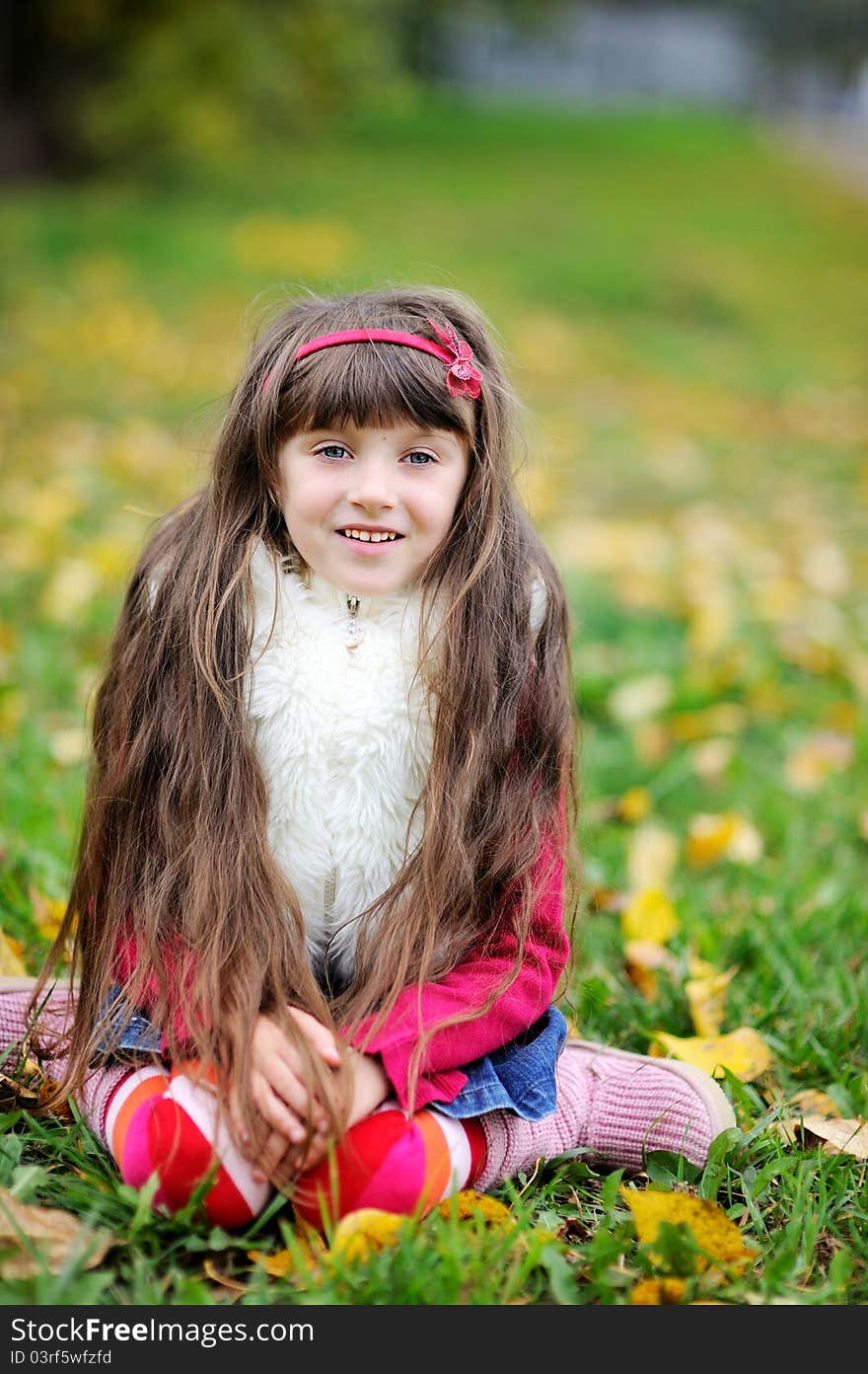 Adorable little brunette girl in pink outfit sitting on a grass. Adorable little brunette girl in pink outfit sitting on a grass