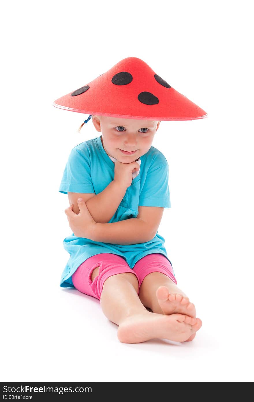 Little girl sitting in studio in funny red hat on her head. Little girl sitting in studio in funny red hat on her head