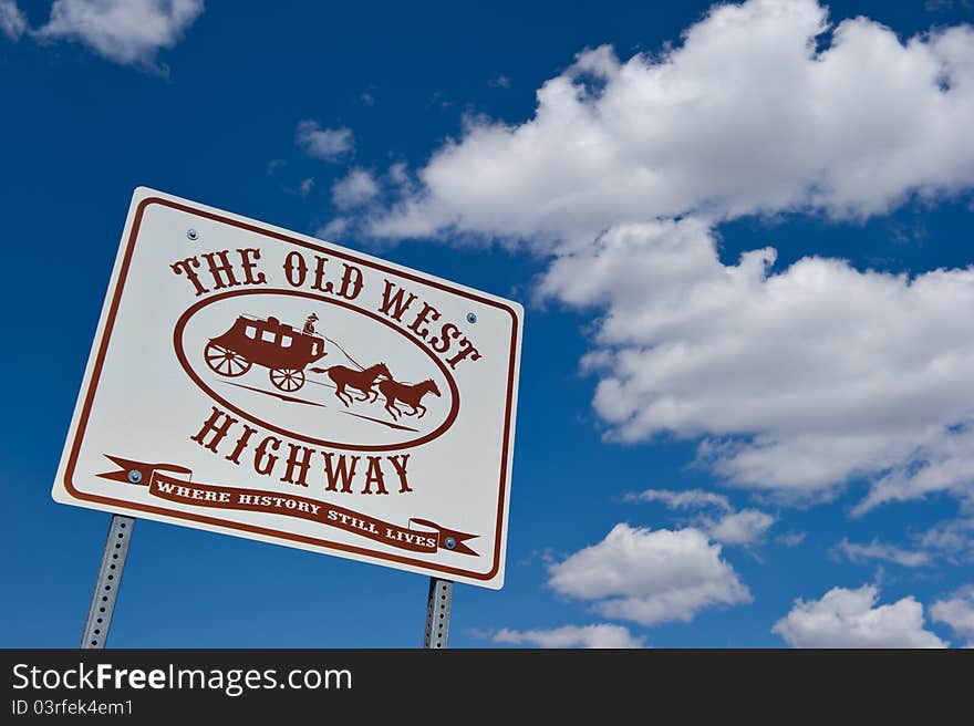 The Old West Highway Road Sign shot against a blue sky and cloudscape. It's where history still lives.