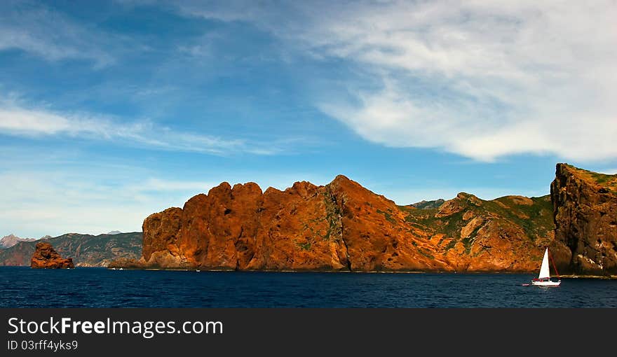 Sail boat near the rugged shore of Corsica, France. Sail boat near the rugged shore of Corsica, France.