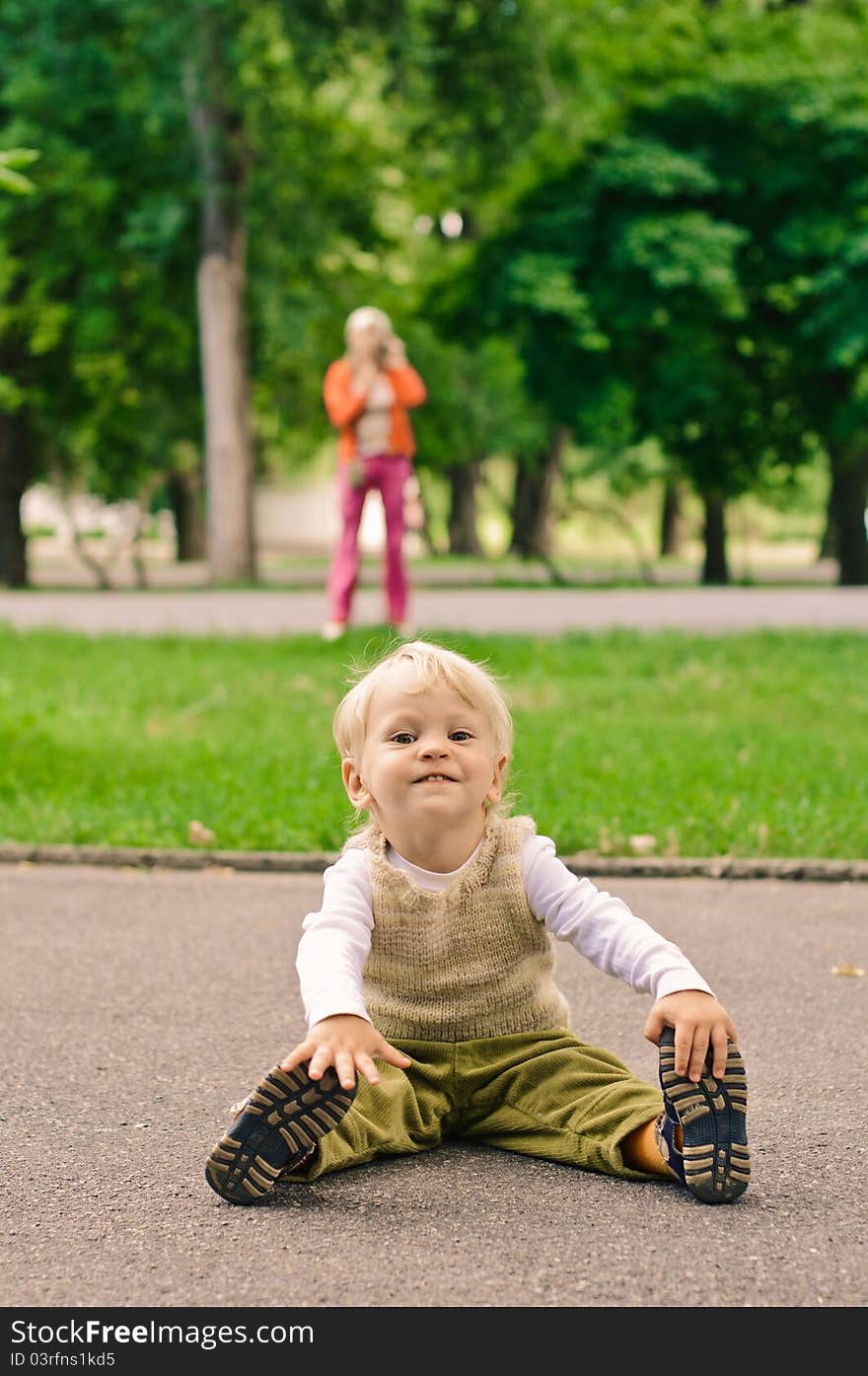 Little boy sits on the footway and her mummy on background. Little boy sits on the footway and her mummy on background