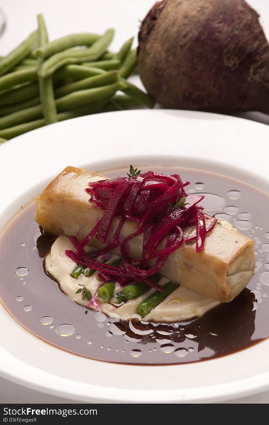 Deep fried duck roll on a bed of green bean mayonnaise and beetroot sauce served on a plate. Deep fried duck roll on a bed of green bean mayonnaise and beetroot sauce served on a plate