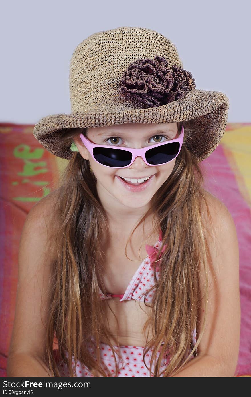 Eight year old girl with hat, sunglasses and beach towel. Eight year old girl with hat, sunglasses and beach towel