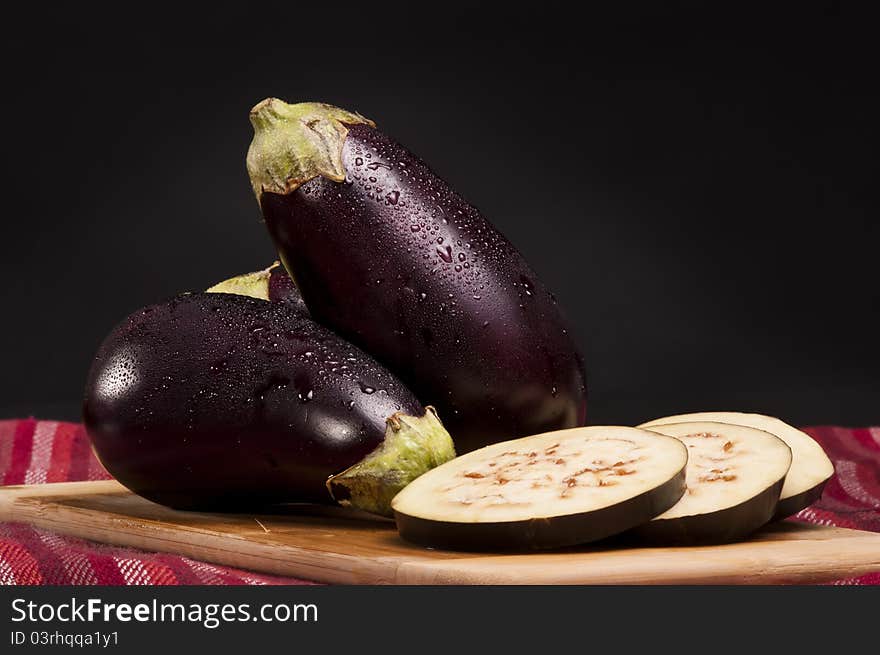 Whole and slices of eggplants on a cutting board