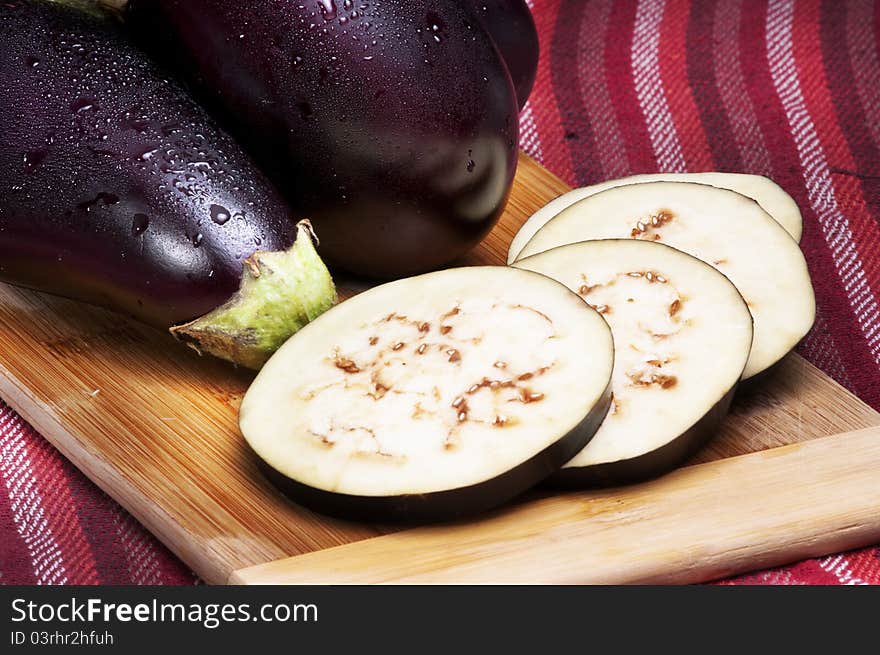 Whole and slices of eggplants on a cutting board