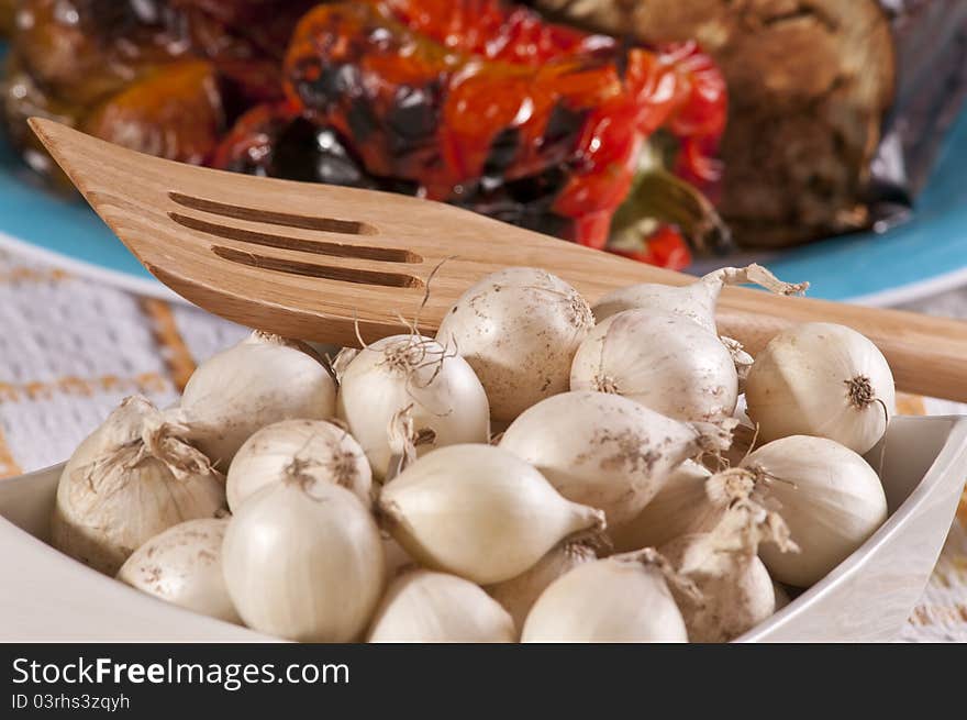 Baby onions in a bowl with roasted vegetables in the background