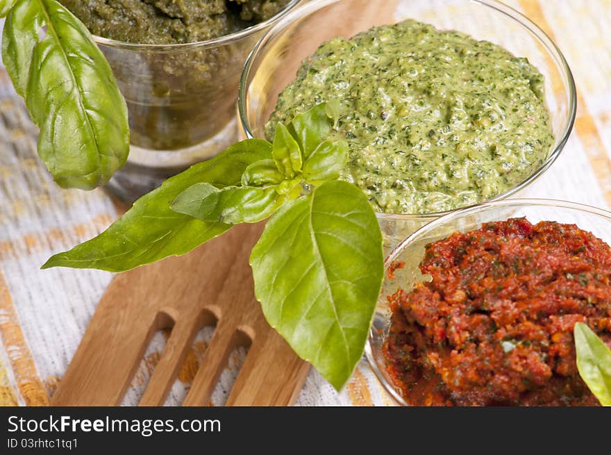 Three kind of pestos in small glasses with few leaves of basil