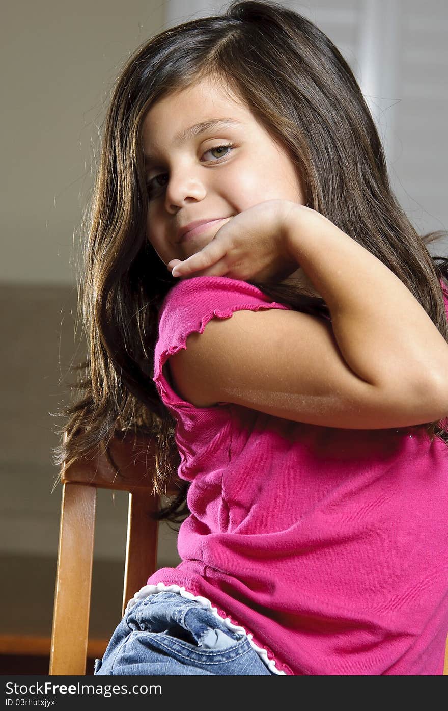 A little girl smiling and posing while sitting in a chair. A little girl smiling and posing while sitting in a chair.