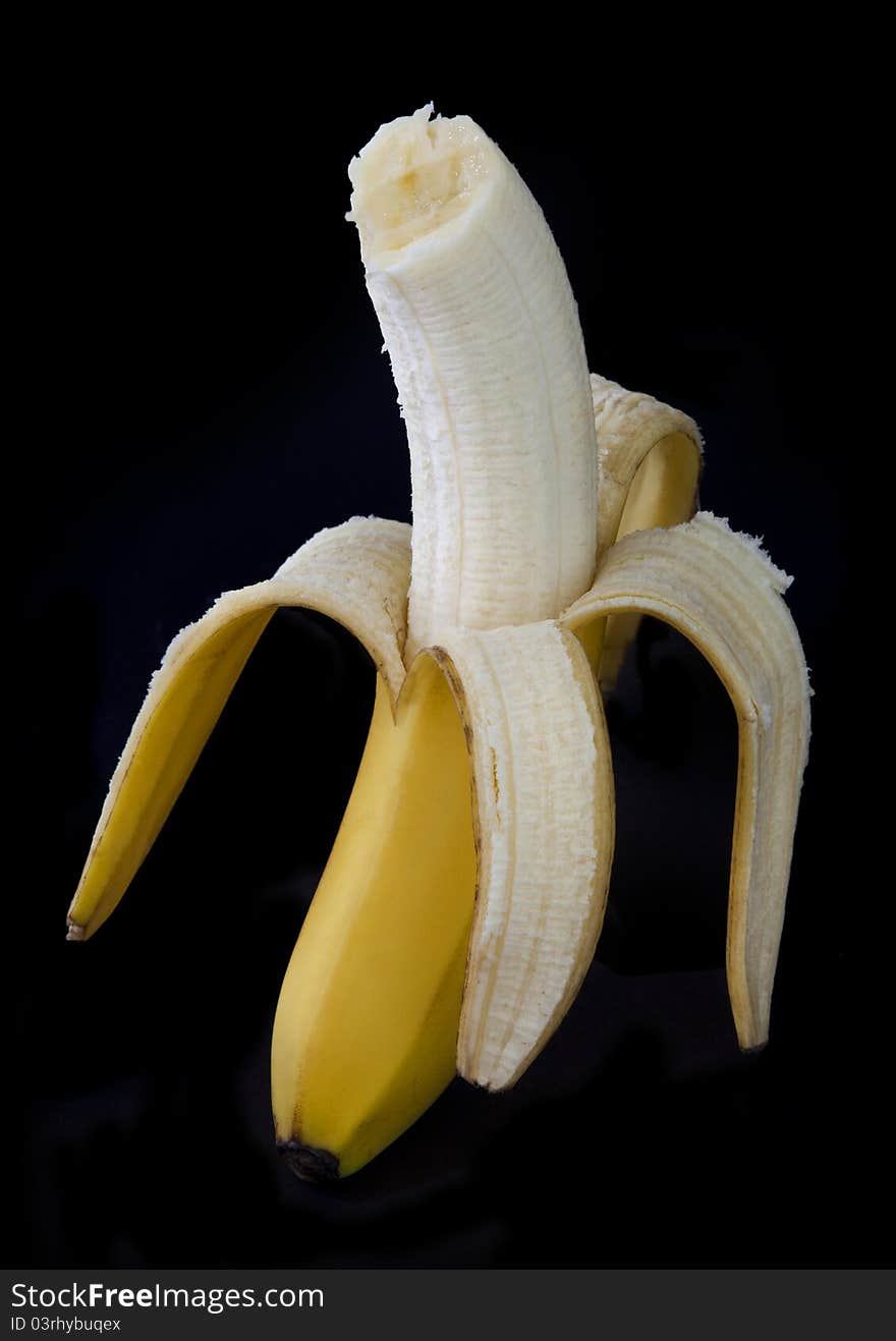 Peeled banana with a bite out of it on a dark background