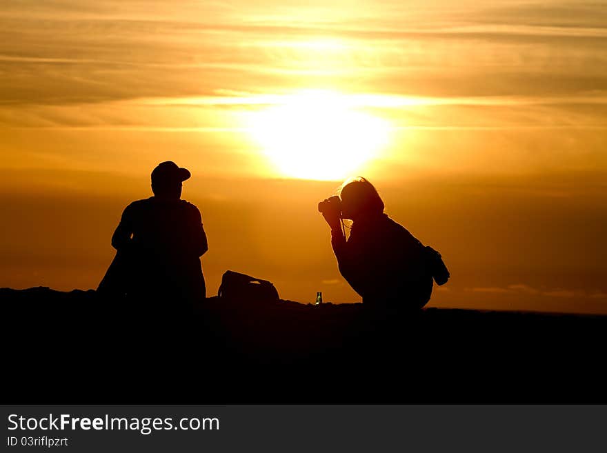 Silhouette of female photographer at sunset