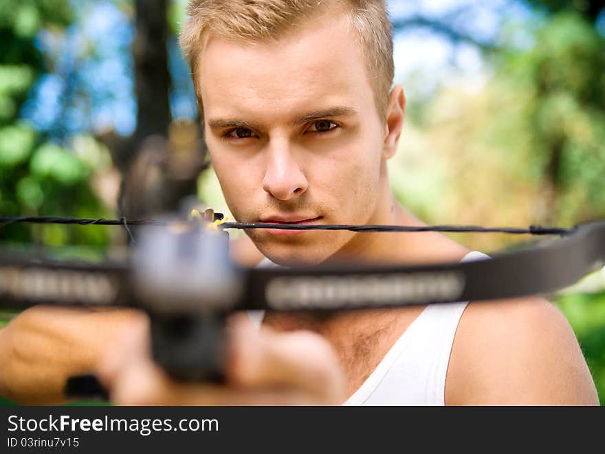 Strong young man with arbalest on the wood background. Strong young man with arbalest on the wood background