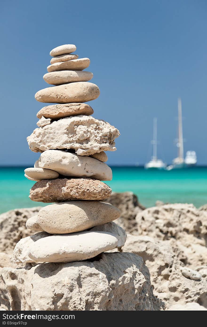 A closeup of stack of pebbles on the beach, two yachts on the background. A closeup of stack of pebbles on the beach, two yachts on the background.