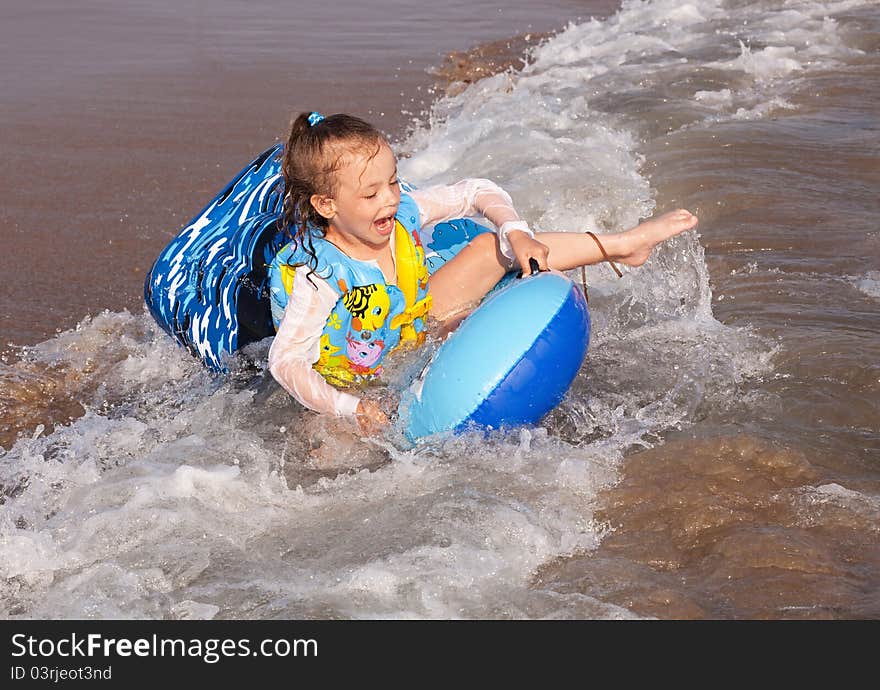 Child rides a wave of the sea.