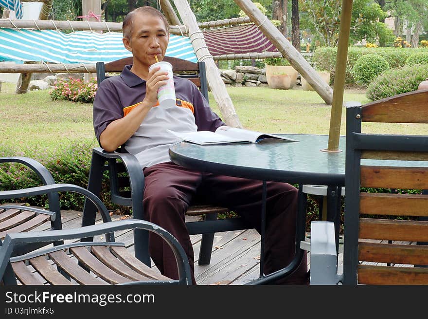 A Visitor who looking at a magazine and drinking. A Visitor who looking at a magazine and drinking