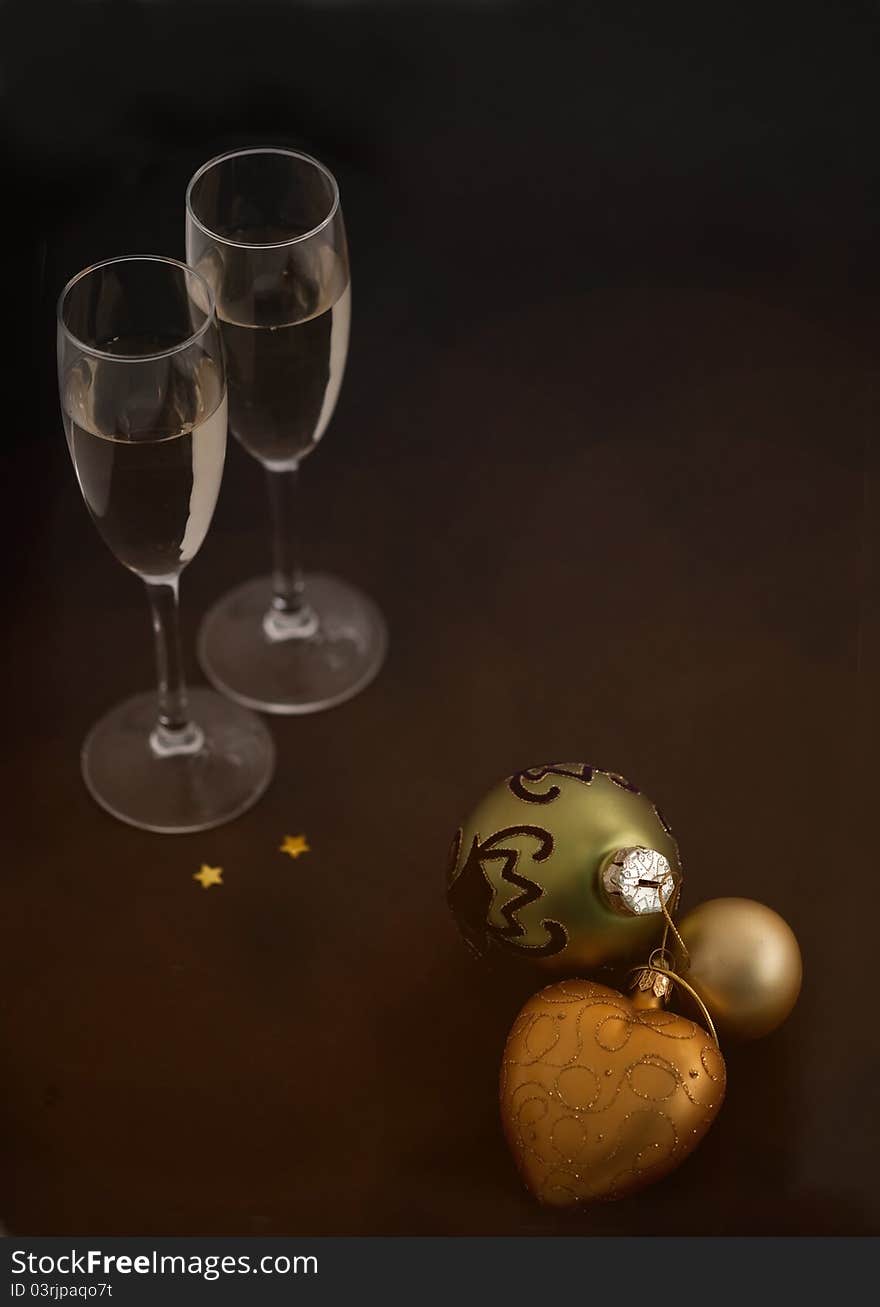 Christmas balls and glasses of champagne on black background