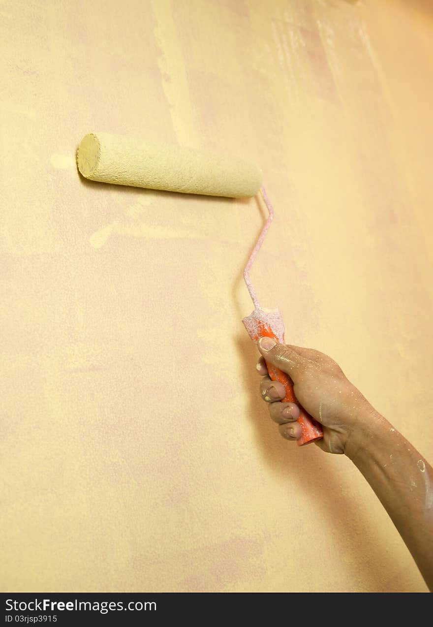 Painting a wall with a paint rol with yellow paint. Painting a wall with a paint rol with yellow paint