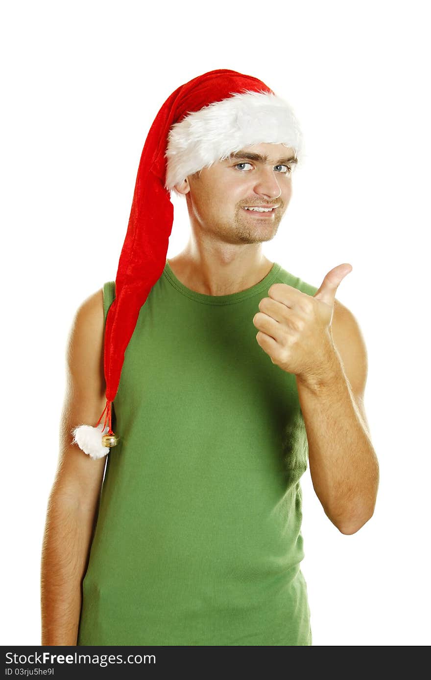 Young man in a Santa Claus hat and green poppy approvingly shows the thumb raised up. Isolated on a white background. Young man in a Santa Claus hat and green poppy approvingly shows the thumb raised up. Isolated on a white background