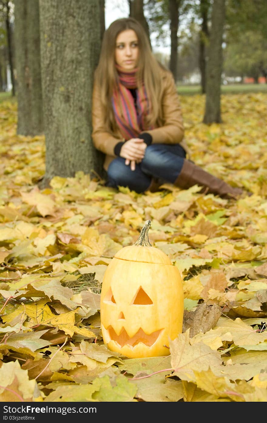 Young girl outdoors in autumn in the park with a pumpkin for Halloween