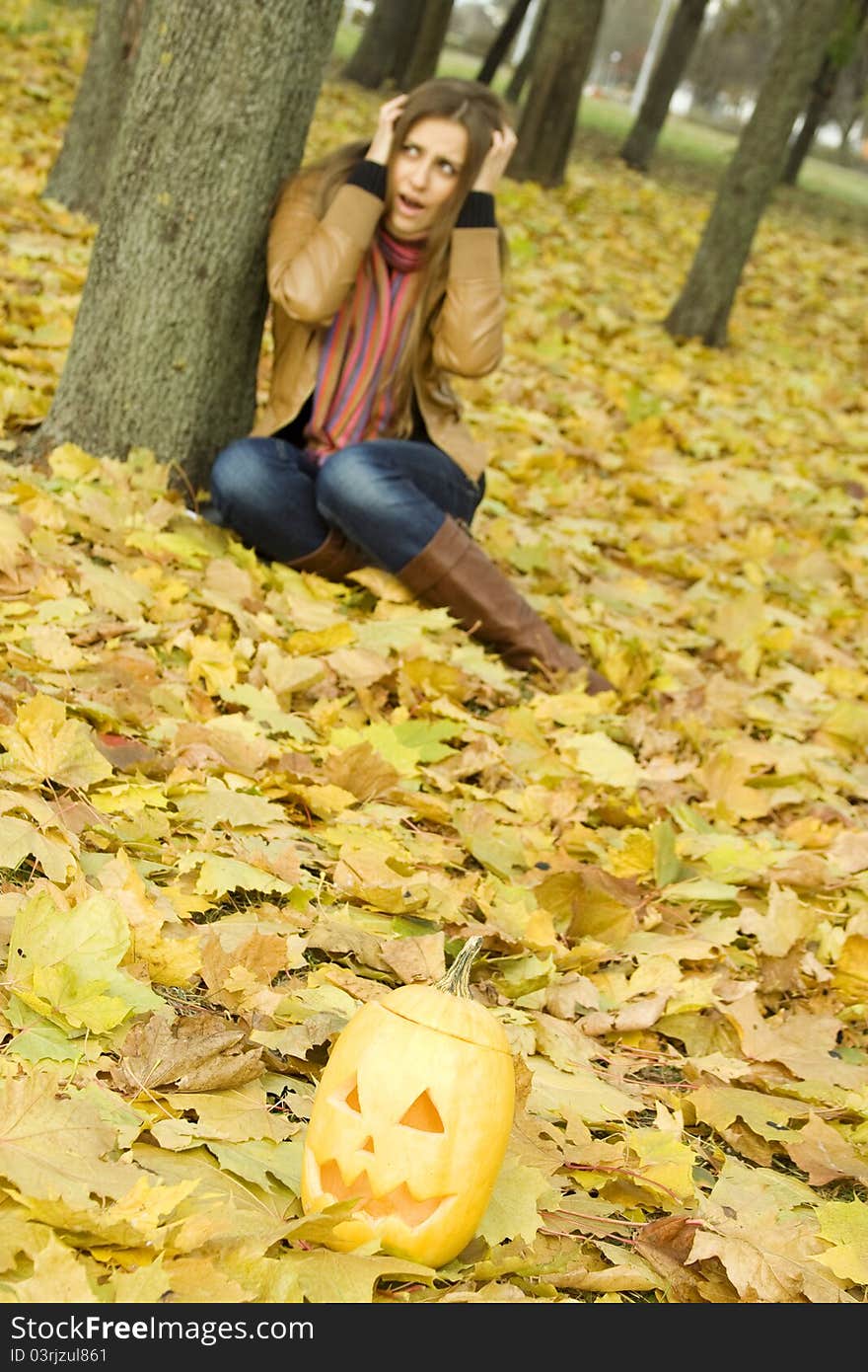 Young girl outdoors in autumn in the park with a pumpkin for Halloween