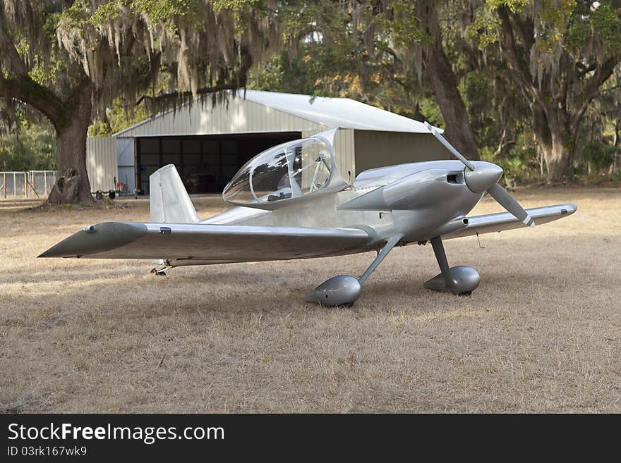 Elegant silver plane awaits its pilot for take-off on grass airstrip. Elegant silver plane awaits its pilot for take-off on grass airstrip.