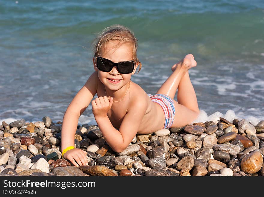 Beautiful girl lying at the seashore in waves and splashes