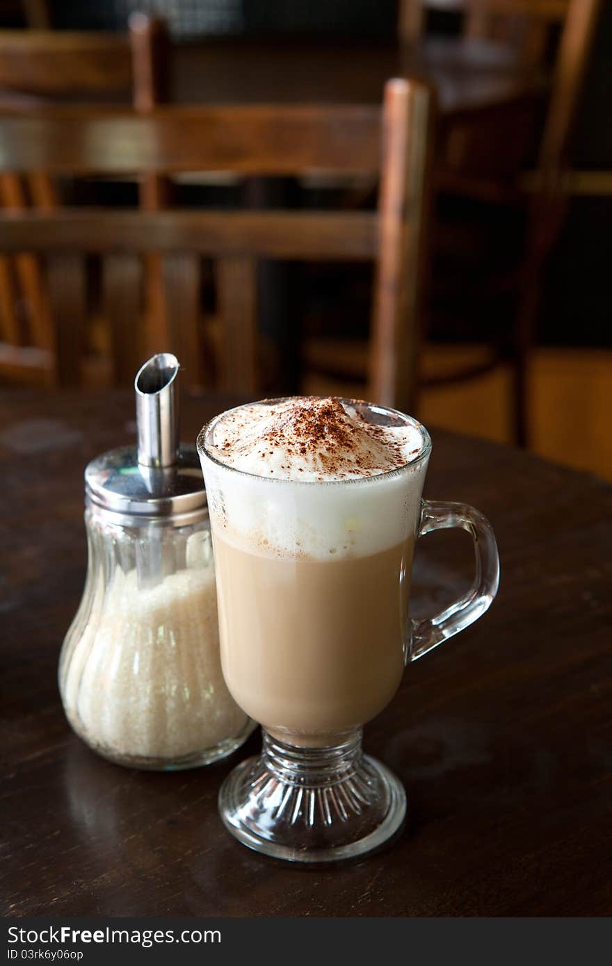 A glass of hot cappuccino complete with foam and cinnamon. A glass of hot cappuccino complete with foam and cinnamon