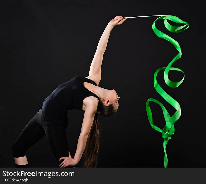 Attractive woman dancing with green ribbon against dark background. Attractive woman dancing with green ribbon against dark background