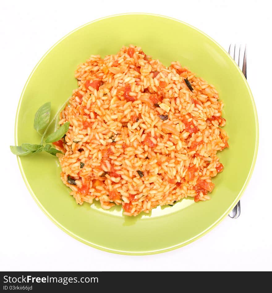 Risotto with tomatoes on a green plate decorated with basil