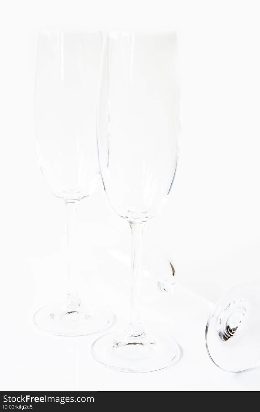 Group of empty champagne glasses on a white background, the two stand side by side, one lying on its side