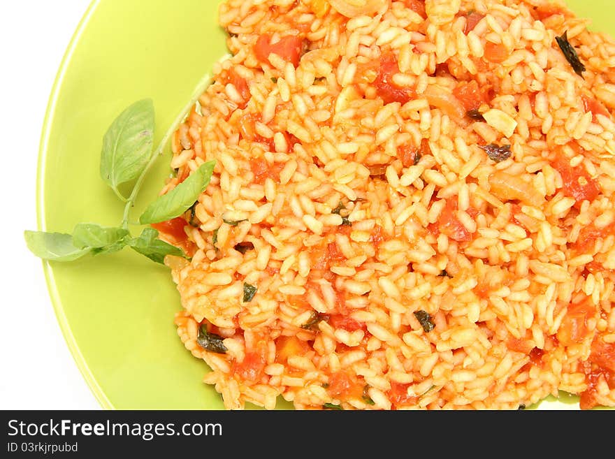 Risotto with tomatoes on a green plate decorated with basil