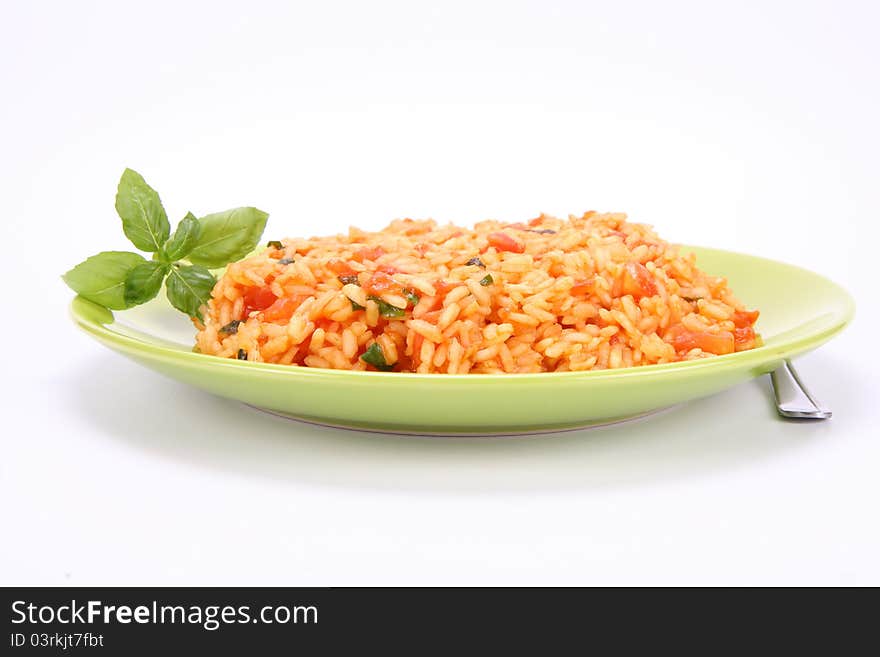 Risotto with tomatoes on a green plate decorated with basil