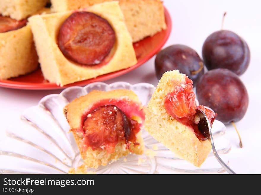 Plum Pie - a piece of it on a fork and more in the background with some fresh plums