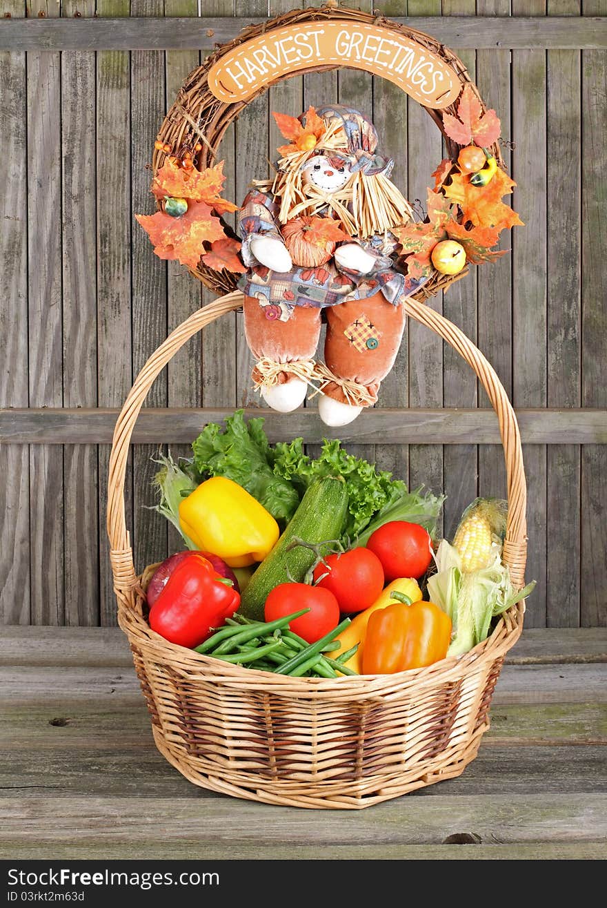 Harvest wreath sitting on top of a basket of vegetables against a weathered fence. Harvest wreath sitting on top of a basket of vegetables against a weathered fence