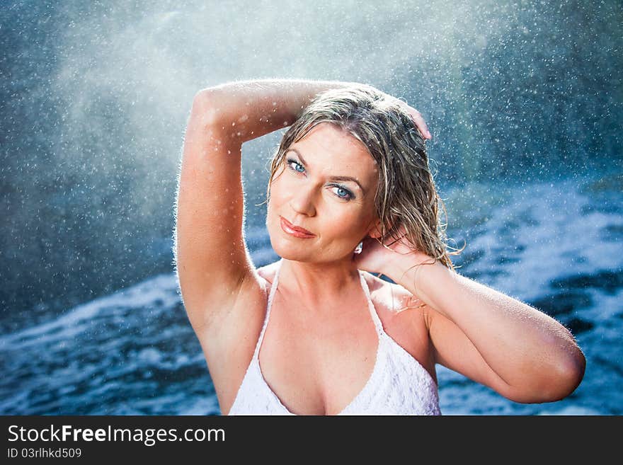 Portrait of beautiful woman enjoying of rest and harmony among sparkling water drops flying from river waterfalls in sunny summer morning. Portrait of beautiful woman enjoying of rest and harmony among sparkling water drops flying from river waterfalls in sunny summer morning