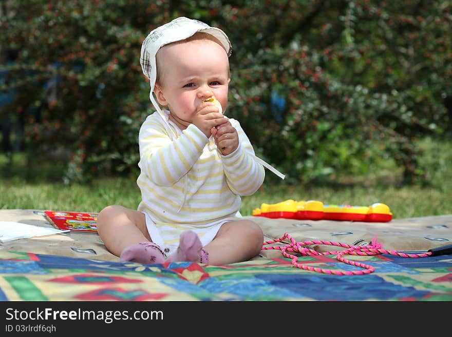 Smiling baby boy on the meadow eating pear