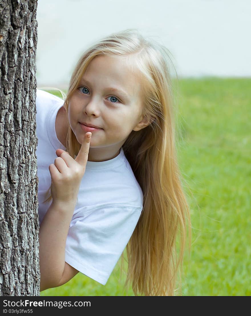 Girl hiding behind a tree in a white shirt. Girl hiding behind a tree in a white shirt