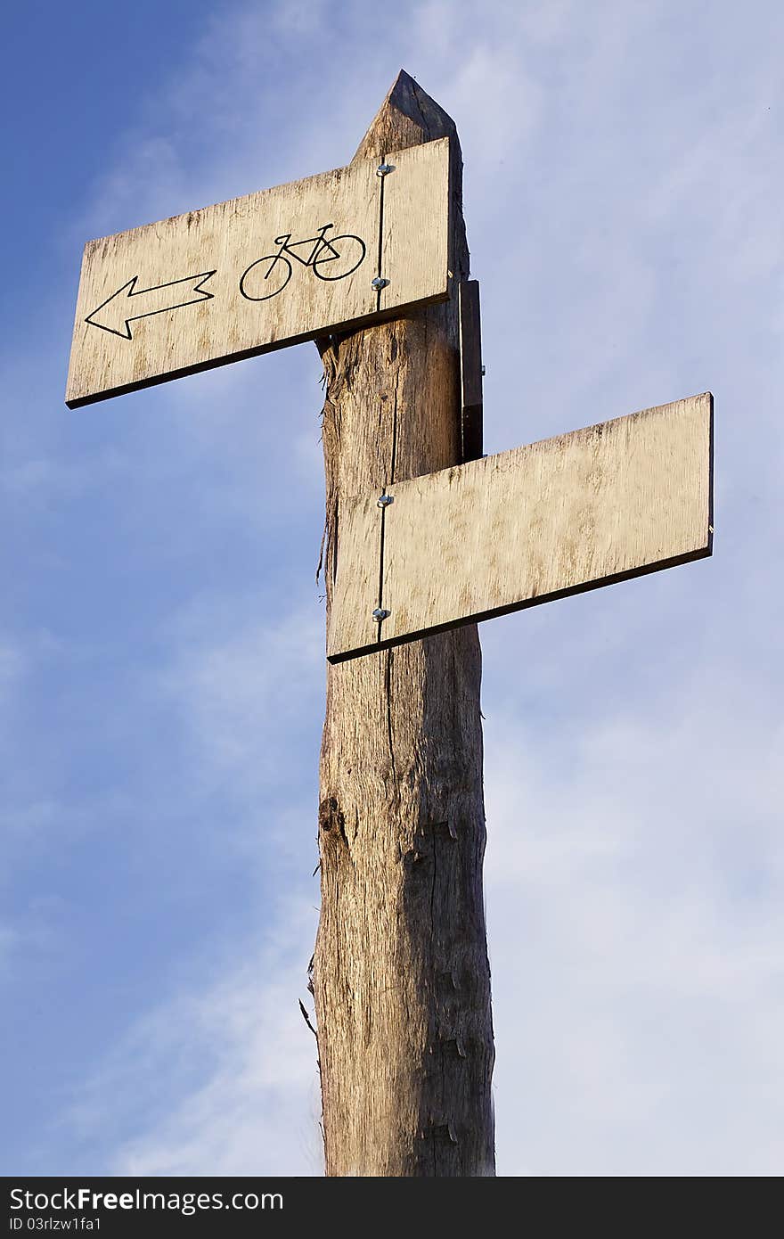 A wooden signpost on a sky background showing a bike route