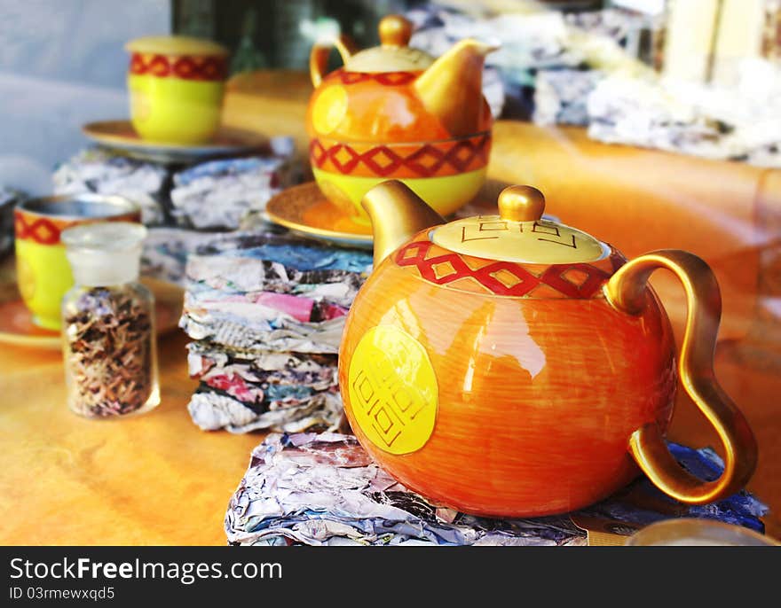 Decorated teapots and teacups in the background in the window