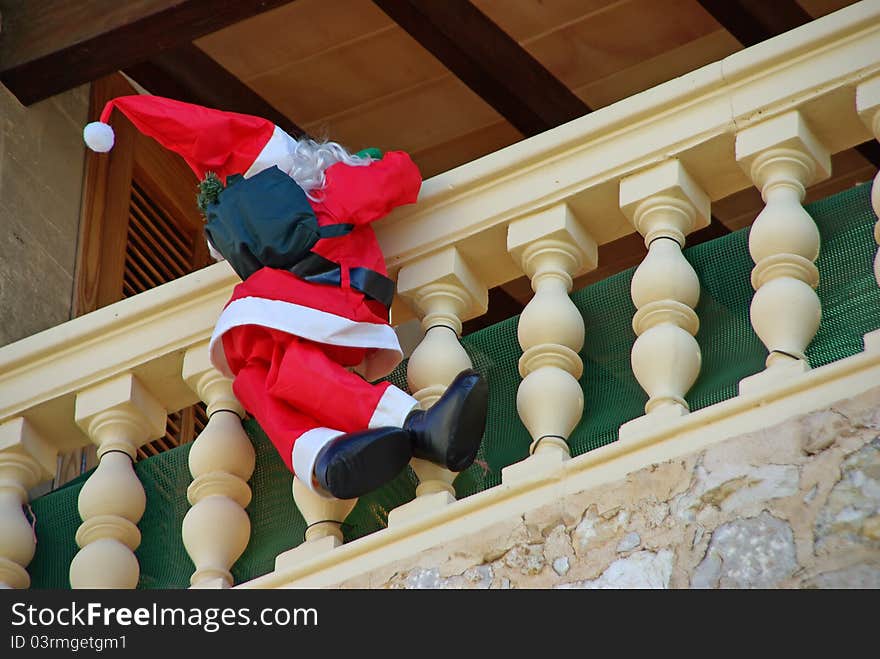 Santa Claus Puppet climbing on the balcony of a house to deliver the presents. Santa Claus Puppet climbing on the balcony of a house to deliver the presents