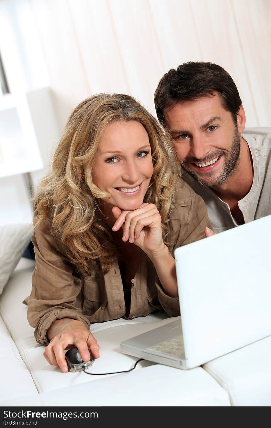 Couple smiling on laptop in their home. Couple smiling on laptop in their home.