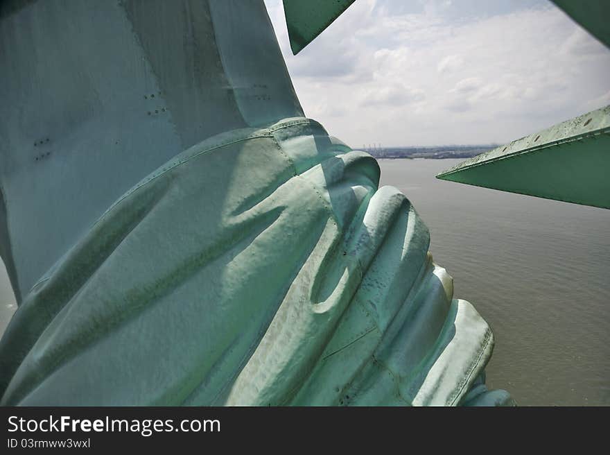 View past the Statue of Liberty's shoulder as seen from her crown with New York Harbor in the distance. View past the Statue of Liberty's shoulder as seen from her crown with New York Harbor in the distance.