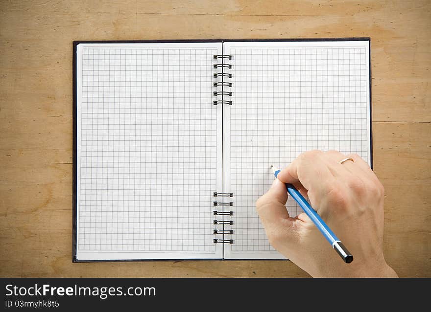 Male hand writing by pencil on checked notebook