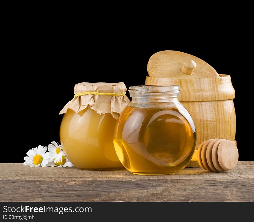 Jar full of honey and stick on blackbackground