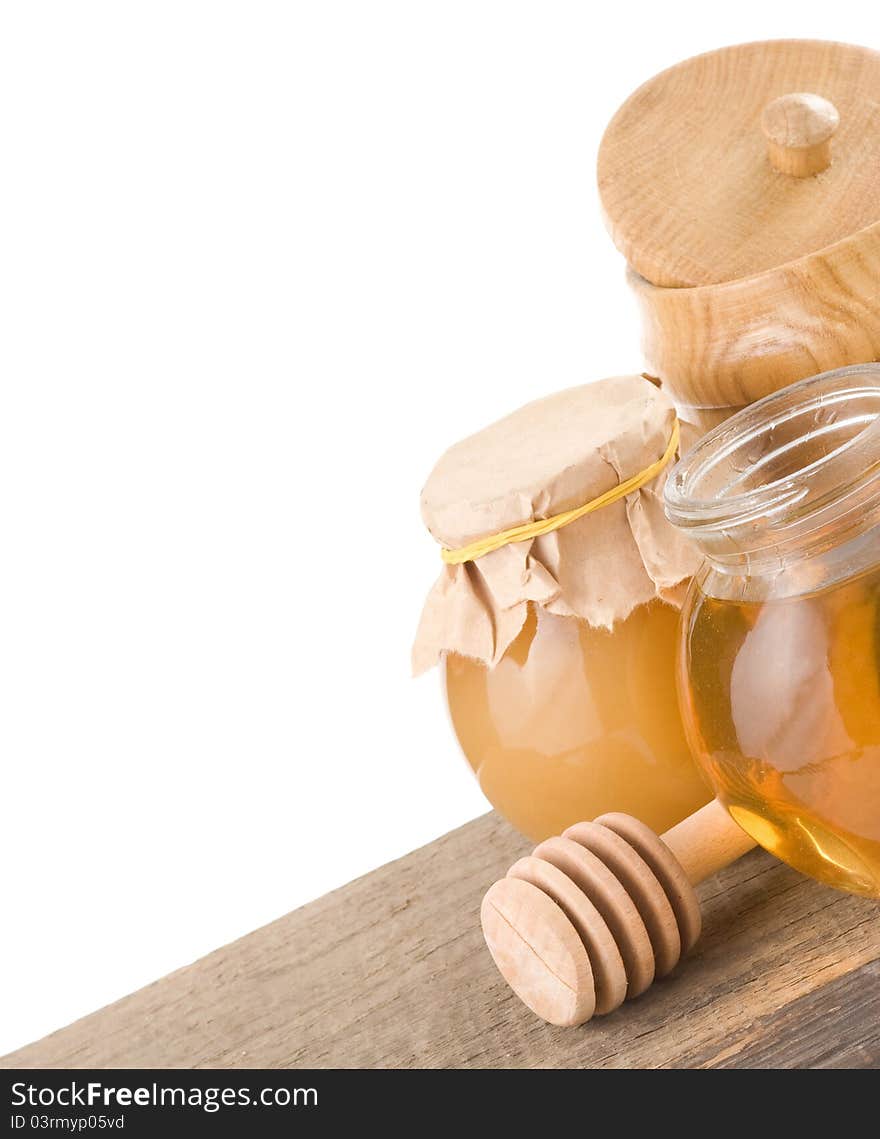 Jar full of honey and stick on white background